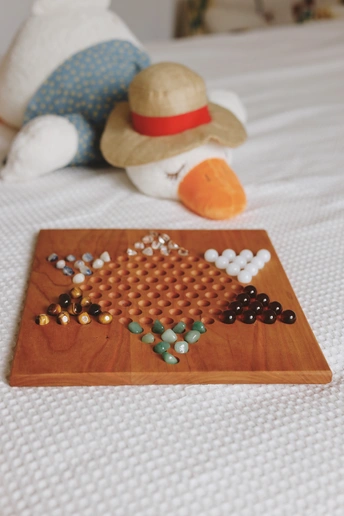 一个放在床上的木托盘 旁边放着一只毛绒动物 上面有一顶帽子和一条项链