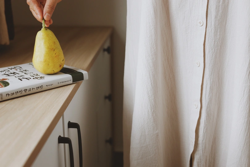 一个穿着白衬衫的人在柜台上拿着一个黄色的柠檬 柜台上有一本书