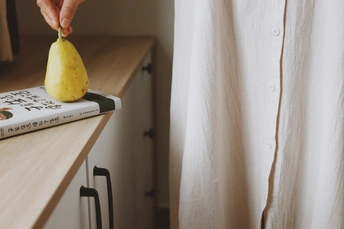 一个穿着白衬衫的人在柜台上拿着一个黄色的柠檬 柜台上有一本书