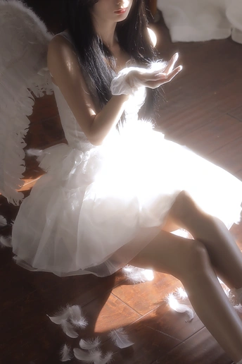 一个穿着白色连衣裙 带有翅膀的年轻女子坐在一个光线昏暗的房间里 地板是木质的。