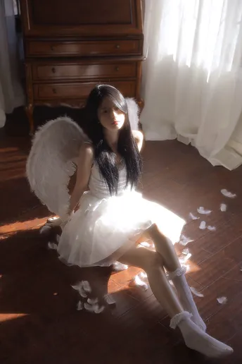 一个穿着天使装 带着白色翅膀的年轻女孩坐在地板上