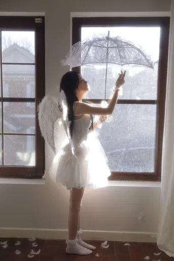 一个穿着白色连衣裙的小女孩 拿着雨伞 凝视着窗户。