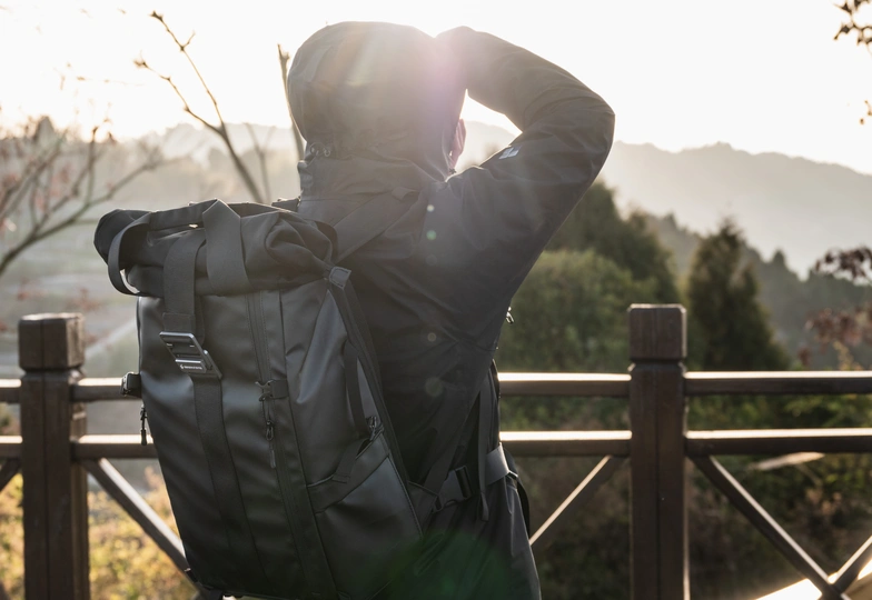 一个背着背包的男人靠在围栏上 正在看太阳。