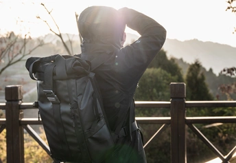一个背着背包的男人靠在围栏上 正在看太阳。