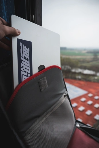 一个人在公交车上背着笔记本电脑 窗外有景色。