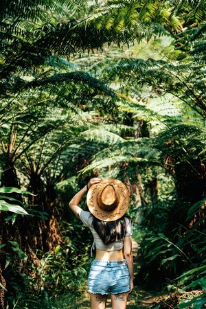 一位戴着帽子的年轻女子站在丛林中的森林里