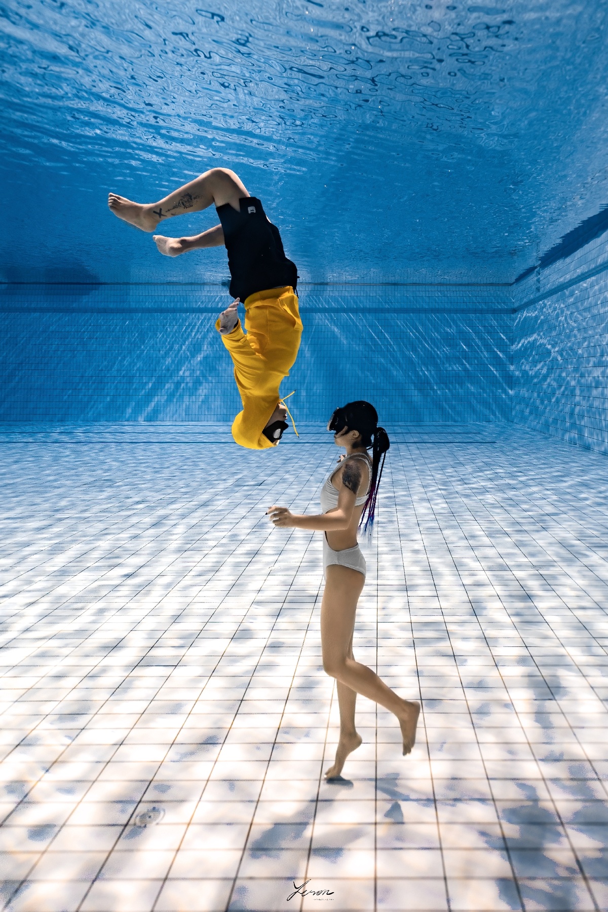 一位穿着黄色的年轻女子跳入一个蓝色的游泳池。