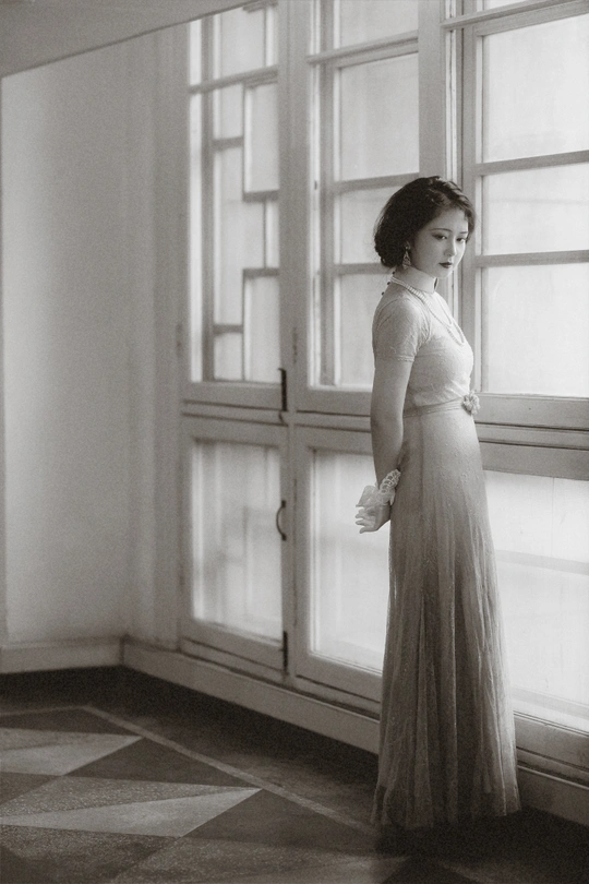 一位穿着连衣裙的女人站在窗户前