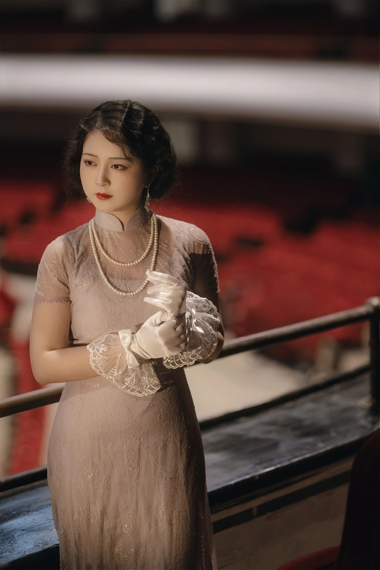 一位穿着连衣裙和手套的女人站在剧院舞台上