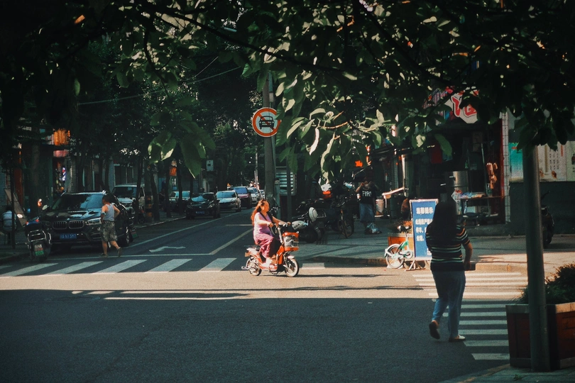 一个人骑着自行车穿过城市的街道 有人在散步 还有一个人在推婴儿车
