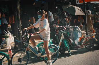 一位戴着口罩的年轻女子骑着自行车沿街而行