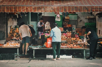 人们站在街上的水果摊前