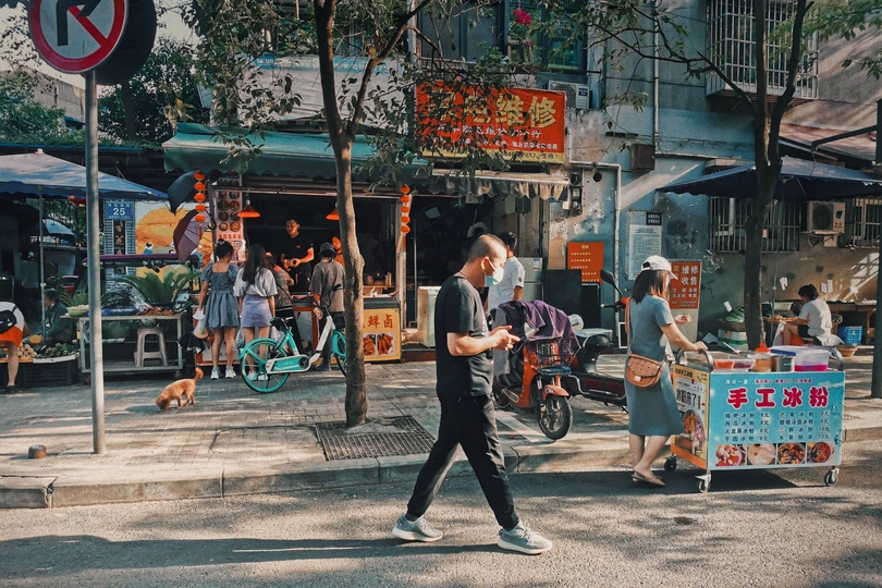 一个男人在繁忙街道旁的人行道上遛狗