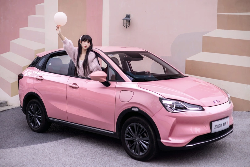 一位年轻的女模特 驾驶一辆粉色汽车