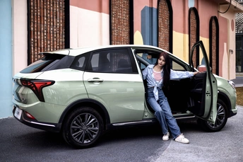 一位女性靠在一辆绿色汽车的车门上