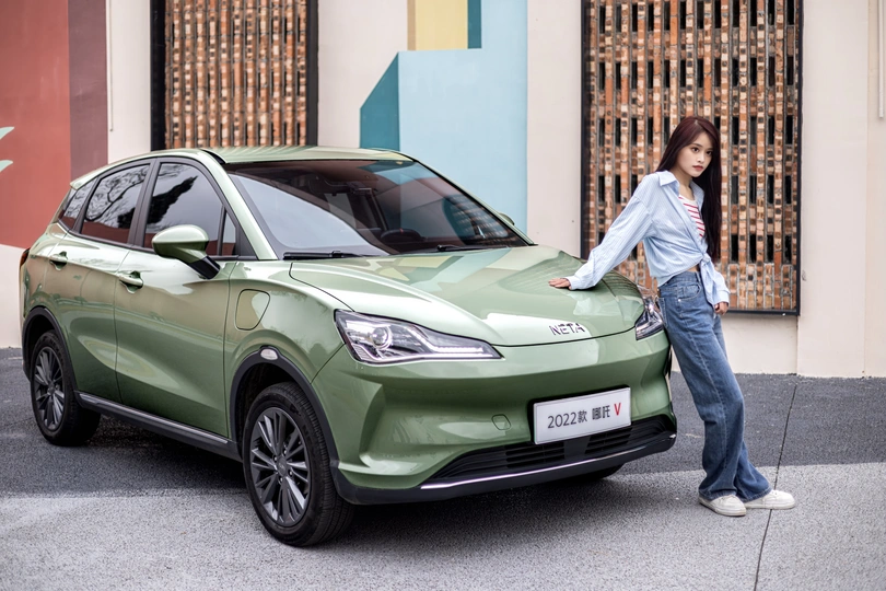 站在一辆绿色汽车旁边的一名女子