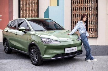 站在一辆绿色汽车旁边的一名女子