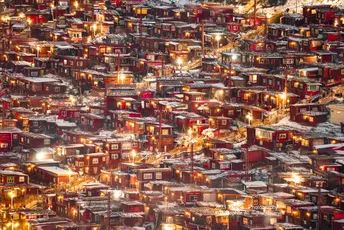 一个被雪覆盖的村庄或小镇 夜晚被圣诞灯照亮。