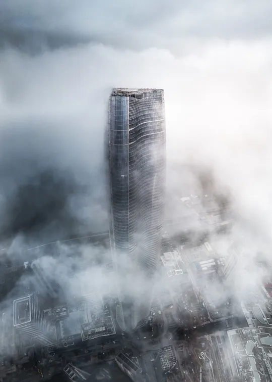 雾气缭绕的城市中一座高楼的图片