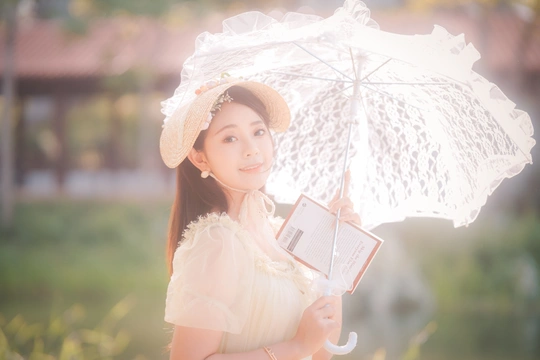 一位穿着白色连衣裙和帽子 手持雨伞的年轻女子