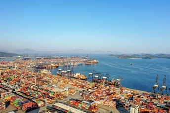 在一大片水域旁边的一个装满了许多集装箱的大港口