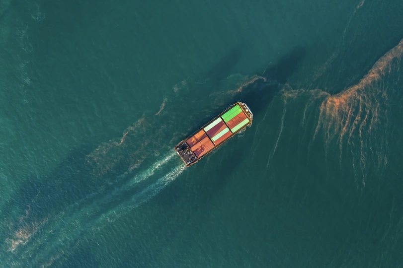 一艘大型集装箱船漂浮在海里 而一艘小船在水中航行的鸟瞰图