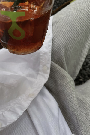 一个穿着白衬衫的人手里拿着一杯茶和一把放在白色餐巾上的勺子