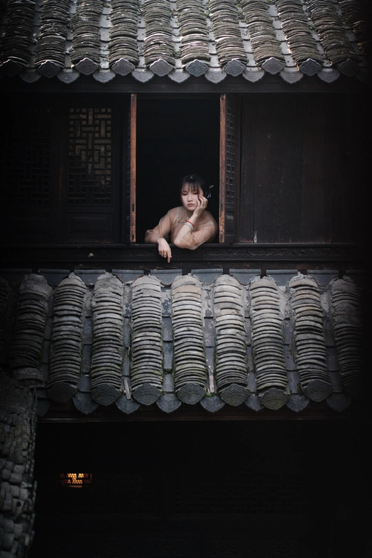 一个年轻人站在一所房子敞开的窗户里