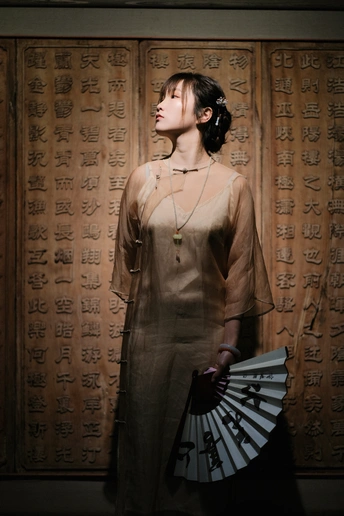一个穿着连衣裙的女人手里拿着一把扇子