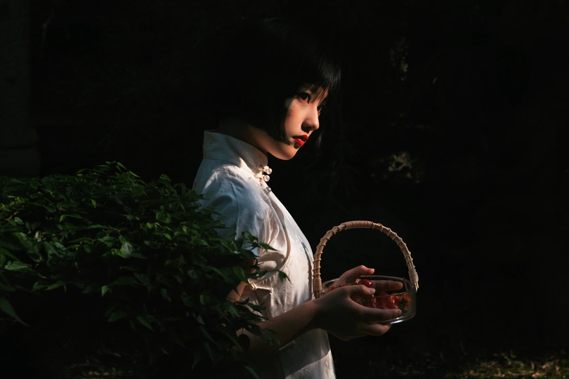 一个拿着白色篮子的年轻女子站在黑暗中