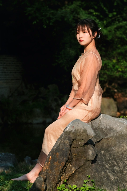 一个年轻女子坐在外面的一块大石头上