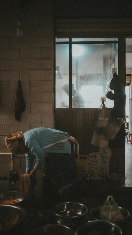 一个厨房里有几个锅和锅铲 一个人站在门口向外看窗户。