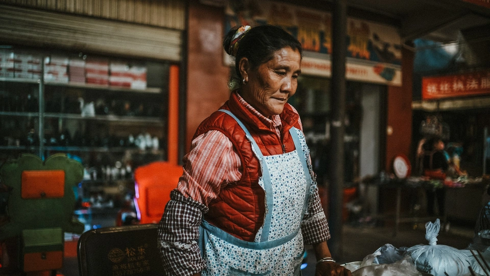 一个戴围裙的女人站在一箱食物旁边
