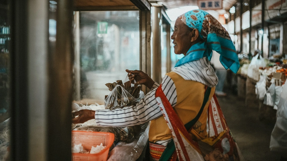 一位妇女站在市场里看着鱼
