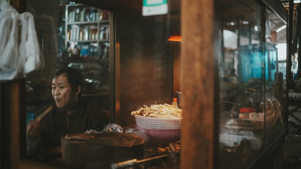 一个女性坐在窗户前吃着一碗爆米花。