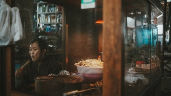 一个女性坐在窗户前吃着一碗爆米花。