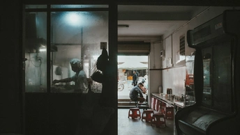 一个黑暗的房间 厨房里有人正在桌子旁准备食物。