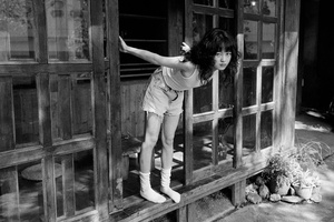 一个小女孩从门廊的木门里爬出来的黑白照片