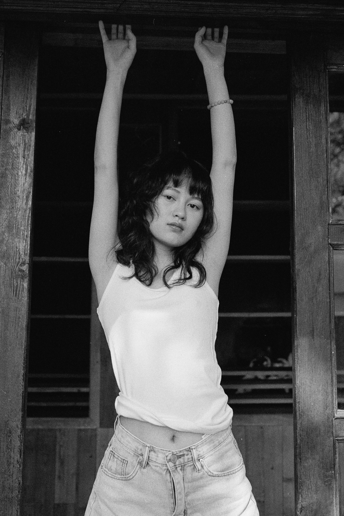 一张黑白照片 照片中一名年轻女子双手举过头顶站在谷仓前