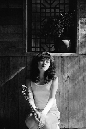 一张黑白照片 照片中一位年轻女子手捧鲜花坐在谷仓里