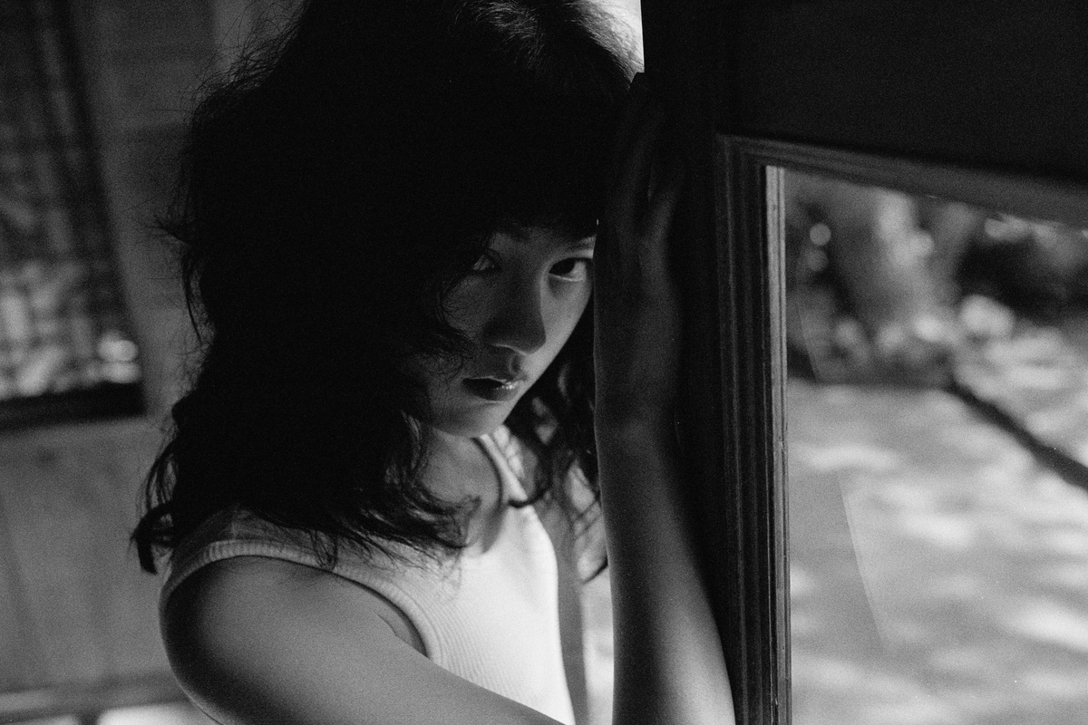 一个穿着黑白衣服从窗户向外看的年轻女孩