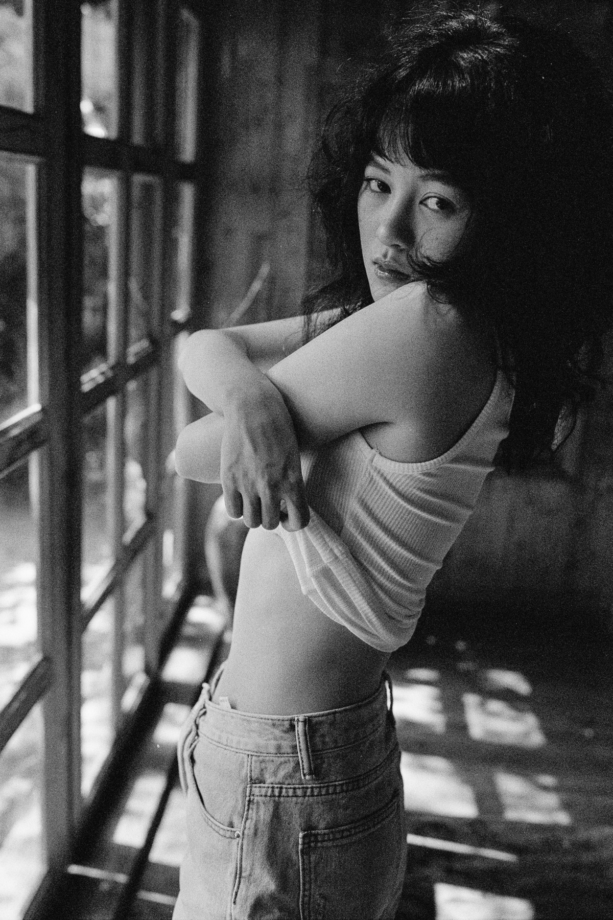 一张年轻女子站在窗前的黑白照片