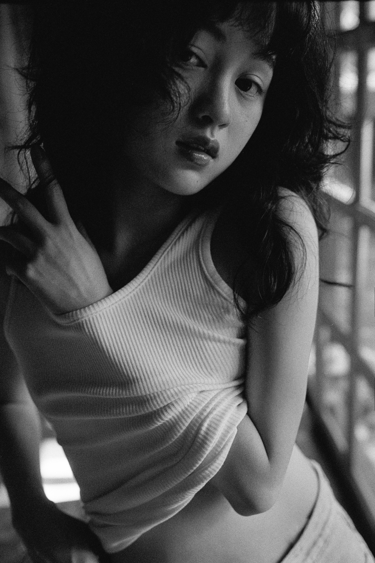 一张年轻女子靠在窗户上的黑白照片