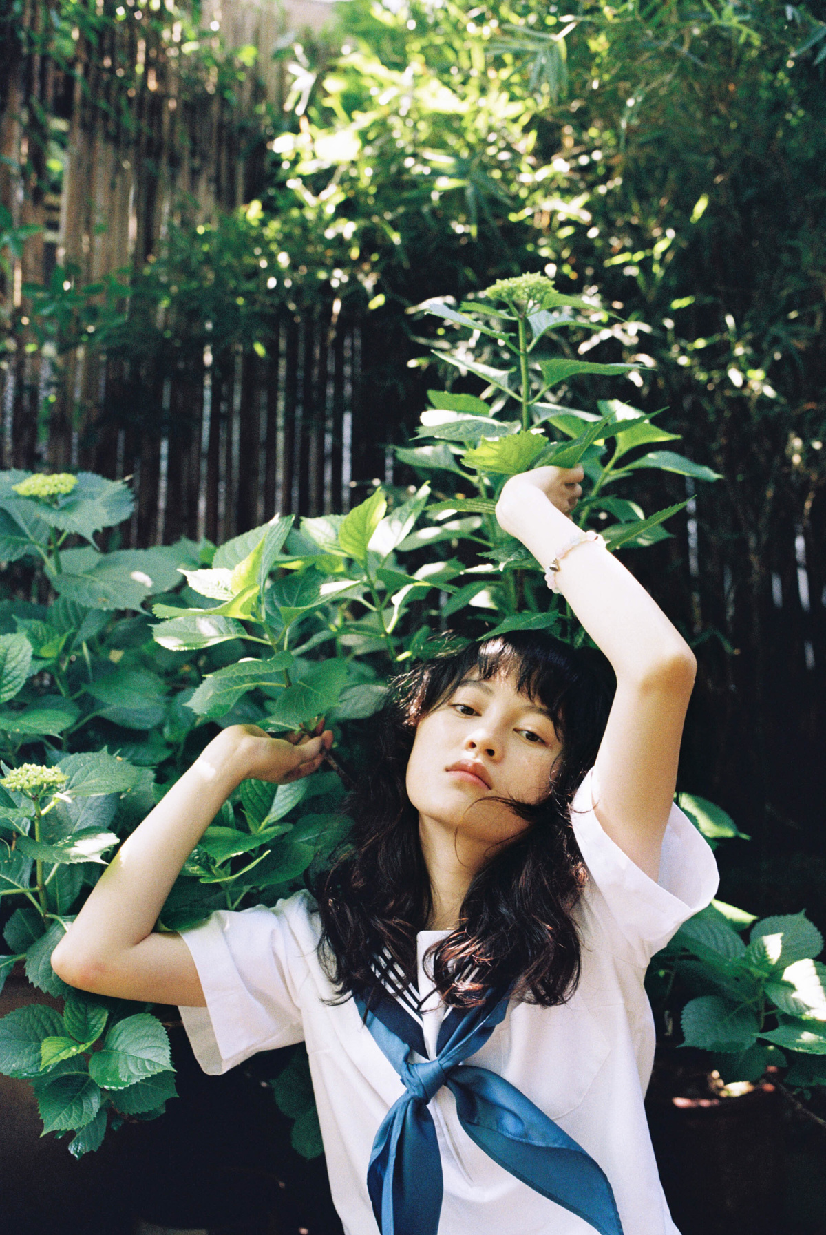 一位穿着白色领带的女青年在花园里拿着植物
