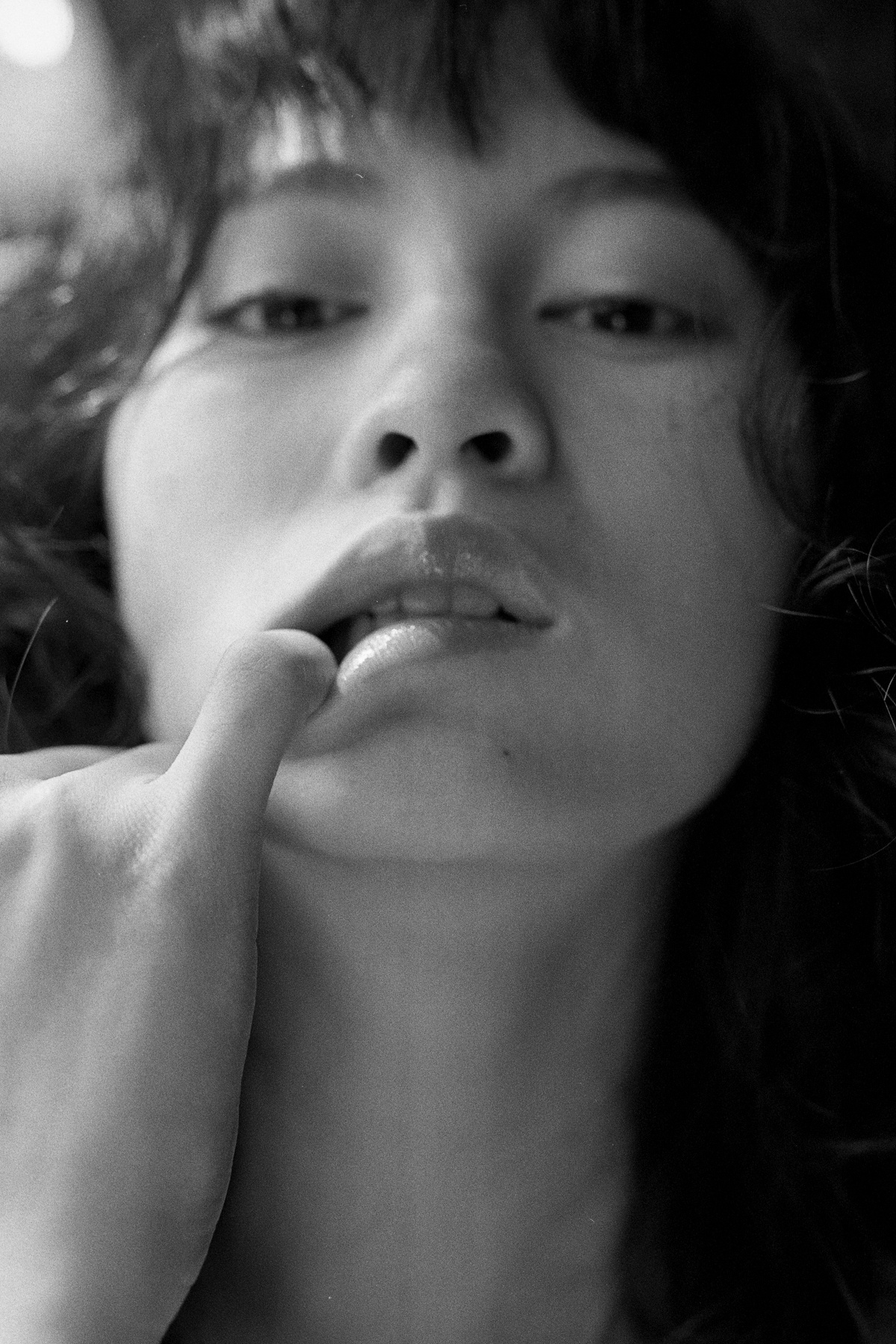 一张黑白照片 一位年轻女子将手放在嘴唇上 将手指放在嘴边。