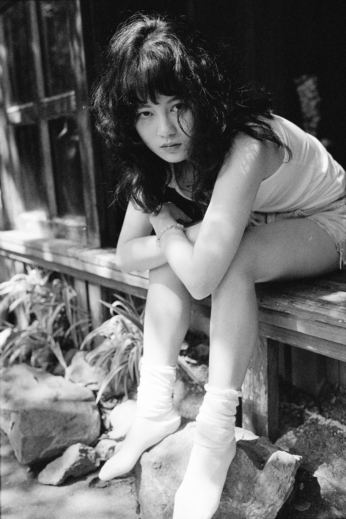 一张黑白照片 一位年轻女子坐在木凳上 双腿交叉