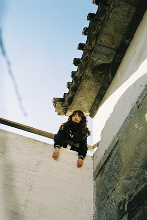 一个小女孩爬上建筑物的边缘 一个年轻人站在屋顶上。