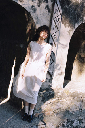 一个穿着白色连衣裙的年轻女子站在一堵墙旁边