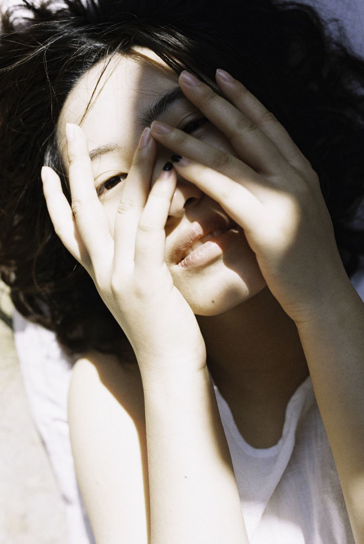 一个年轻女子用手遮住脸在阳光下