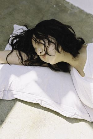 一个留着黑头发的年轻女子穿着白色衬衫躺在人行道上